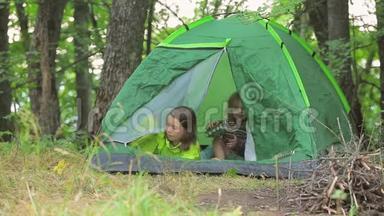 孩子们在绿色的<strong>帐篷</strong>里玩耍，在森林的空地上玩耍。 关上<strong>帐篷</strong>里的格子..